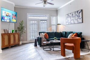 Ein Wohnzimmer mit einer Couch, einem Couchtisch und einem an der Wand befestigten Fernseher, der Streaming-Dienste anzeigt.