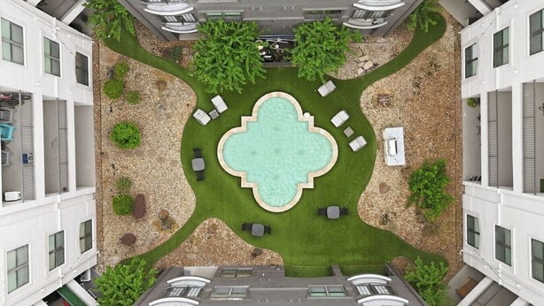 A rooftop pool with surrounding lounge chairs and a central fountain, surrounded by greenery and a pebble path. - Sleeps 5 | Downtown & Sport Stadiums Nearby | Pool + Gym + Free Parking (Houston)