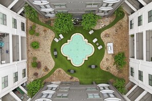 A rooftop pool with surrounding lounge chairs and a central fountain, surrounded by greenery and a pebble path. - Sleeps 5 | Downtown & Sport Stadiums Nearby | Pool + Gym + Free Parking (Houston)
