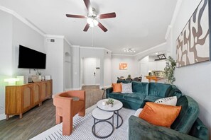 Ein modernes Wohnzimmer mit Sofa, Sessel, Couchtisch und Fernseher.