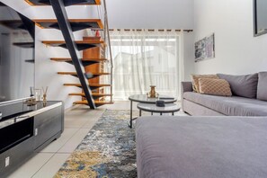 Ein modernes Wohnzimmer mit einer Couch, einem Couchtisch, einem Fernseher und einer Treppe.