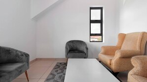 Ein modernes Wohnzimmer mit weißer Decke, einem kleinen Fenster und zwei Sofas.
