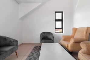 Ein modernes Wohnzimmer mit weißer Decke, einem kleinen Fenster und zwei Sofas.