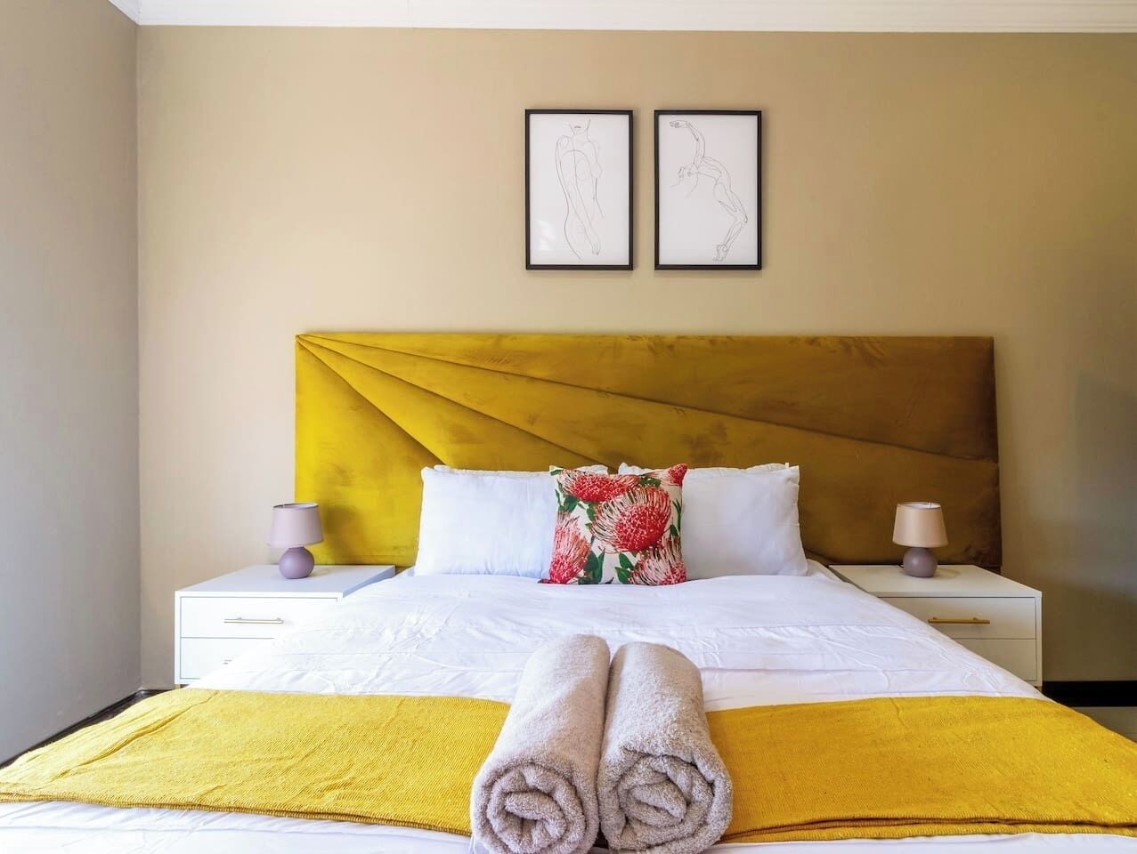 A hotel room with a bed, two nightstands, a headboard, and two framed pictures on the wall.
