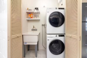 A compact laundry room with a washing machine, dryer, and a sink. - Sunset@ArecaHomes ~ Beach Access~Pool & Water Park (Discovery Bay, St Ann)