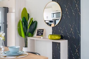 A modern reception desk with a welcome sign, a mirror, a potted plant, and a green bowl. - Sunset@ArecaHomes ~ Beach Access~Pool & Water Park (Discovery Bay, St Ann)