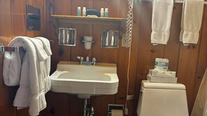 Un bagno piccolo ma funzionale, con lavandino, specchio, servizi igienici e portasciugamani.