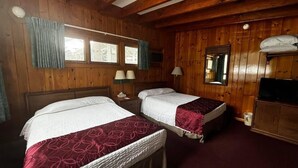 Une chambre avec deux lits, des murs en bois, une télévision et une fenêtre.