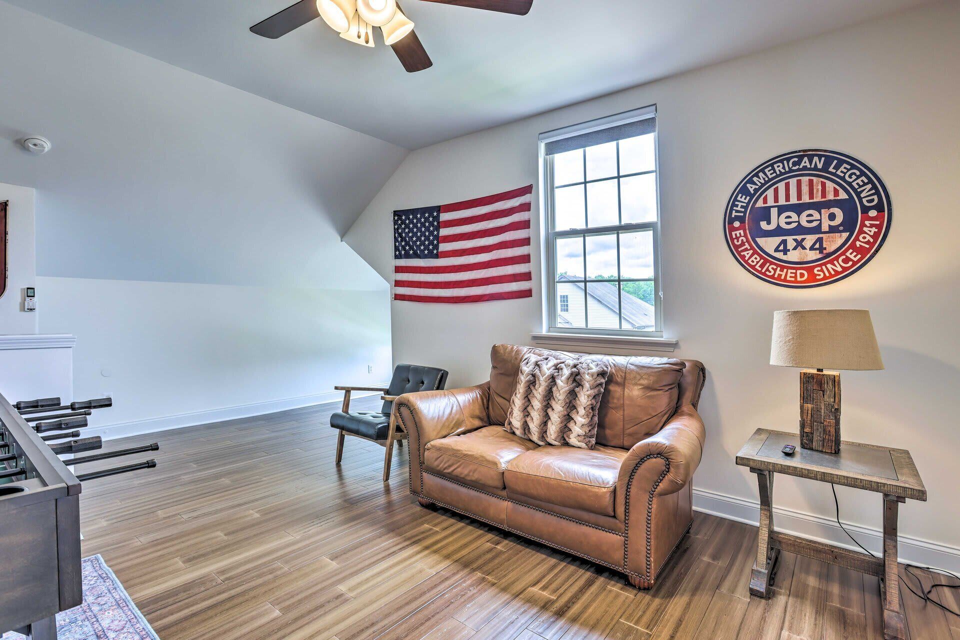 A spacious room with a leather sofa, a flag, a Jeep logo, and a window.