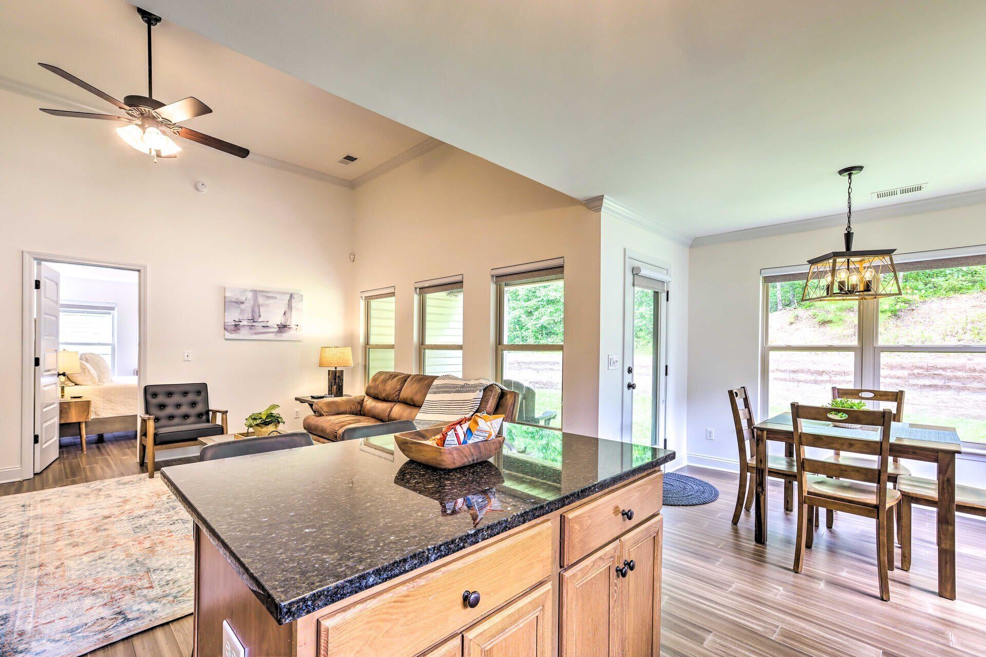 A spacious kitchen with a large island, a dining area with wooden furniture, and a ceiling fan.