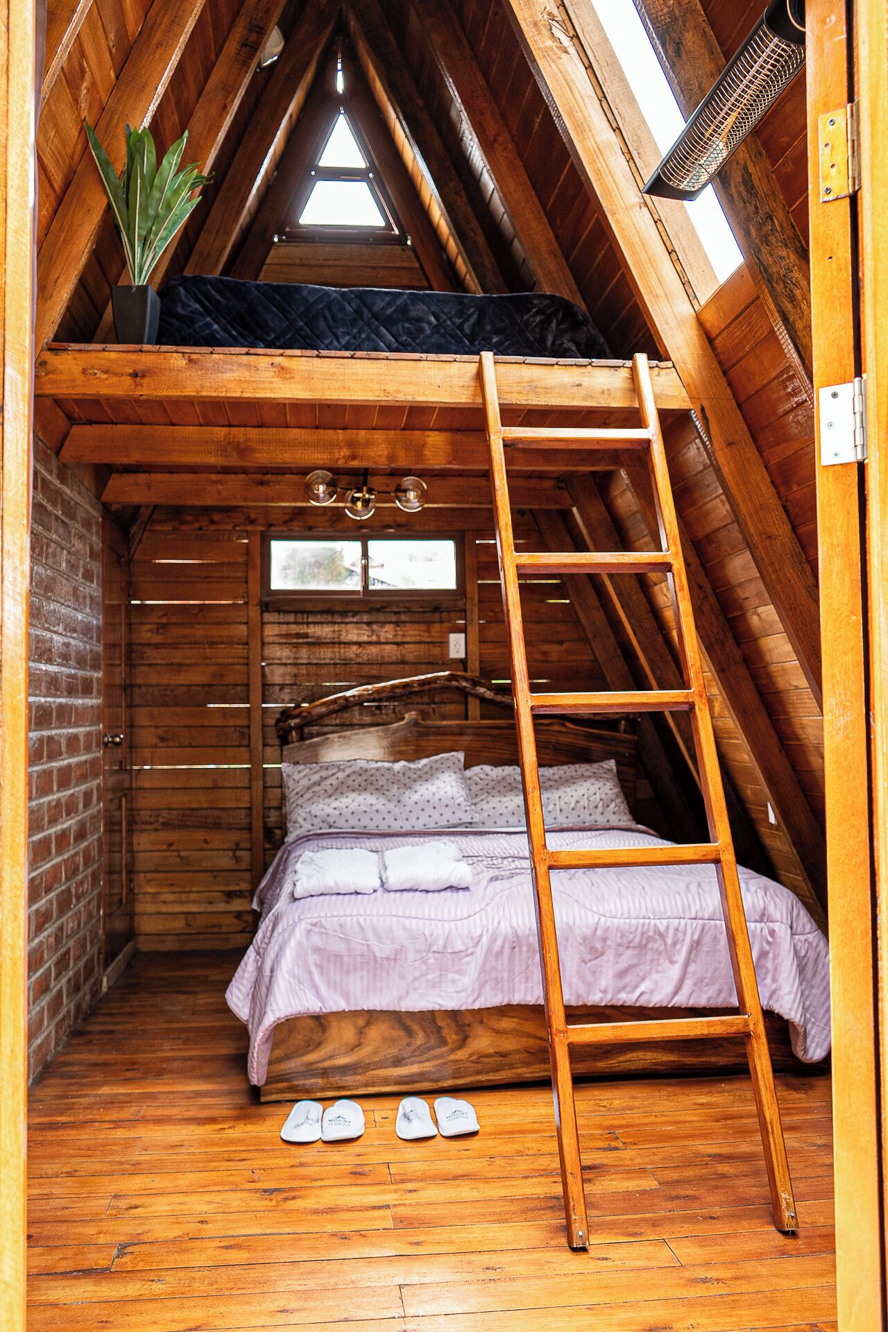 Ein Schlafzimmer im Loft-Stil mit Holzleiter, Bett und Dachfenster.
