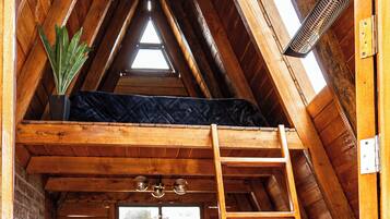 Ein Schlafzimmer im Loft-Stil mit Holzleiter, Bett und Dachfenster.