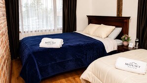 Habitación de hotel con cama doble, mesita de noche con botella de agua, planta pequeña en maceta y cartel con el número de la habitación.