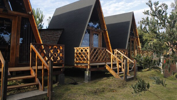 Una cabaña moderna tipo A con terraza de madera y escaleras que conducen a la entrada.