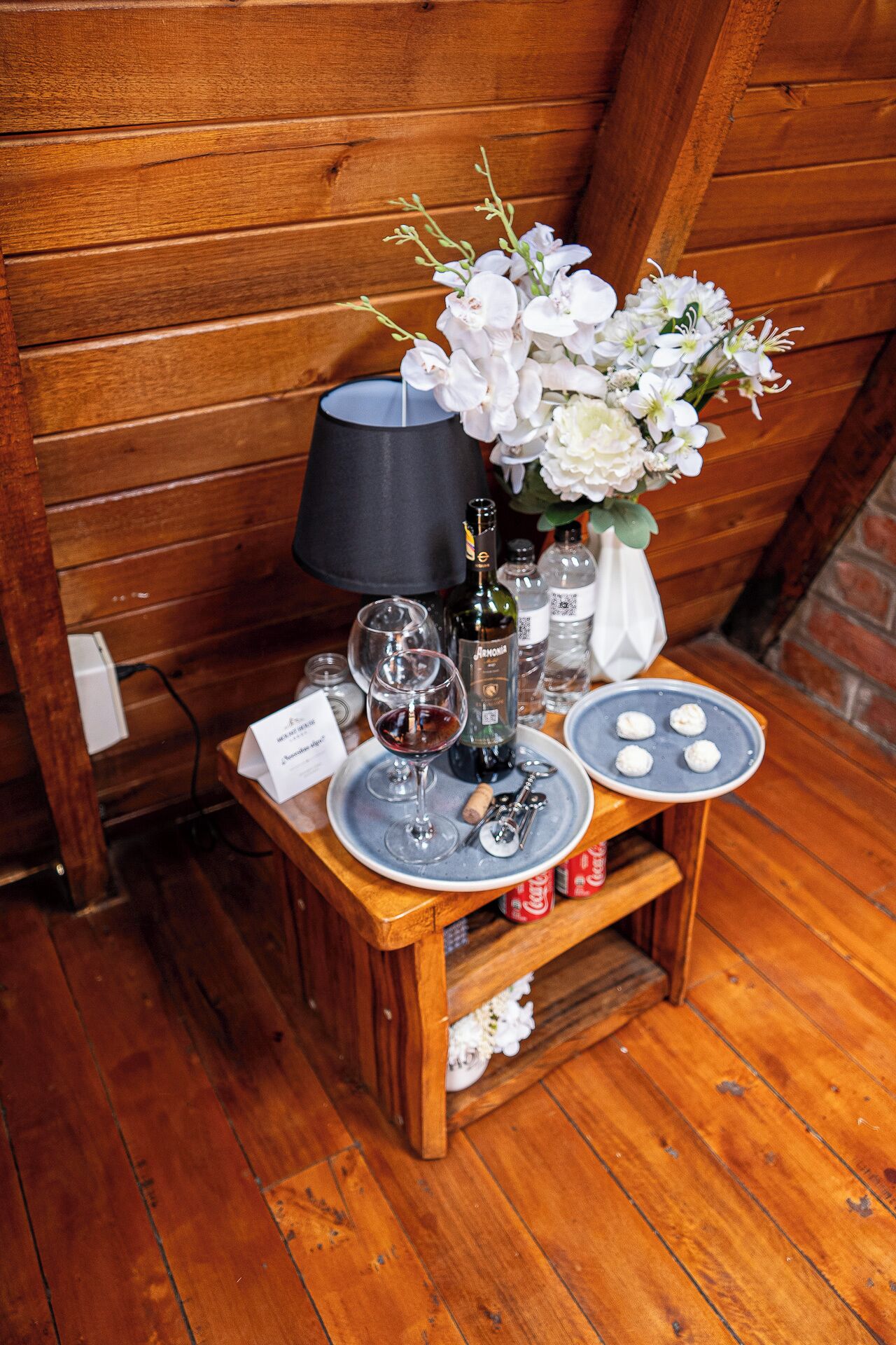 Une table en bois avec une bouteille de vin, des verres, une bougie et une assiette de nourriture.