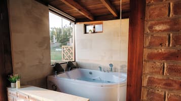 Eine Holzhütte mit einer großen Badewanne, einem Fenster und einer Backsteinmauer.
