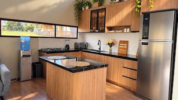 Une cuisine moderne dotée d’un îlot central, d’appareils électroménagers en acier inoxydable, de meubles de rangement en bois et d’un distributeur d’eau.