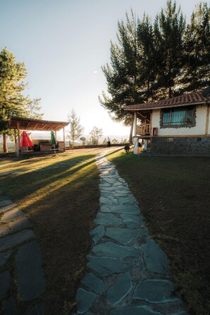 Un sendero de piedra que conduce a una casa con techo de tejas y una antena parabólica.