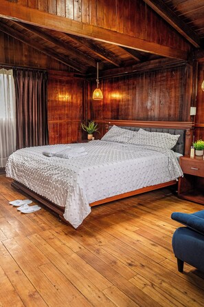 Un dormitorio con paneles de madera, una cama, una lámpara colgante y una mesita de noche.