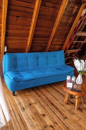 A blue sofa in a wooden room with a sloped ceiling.