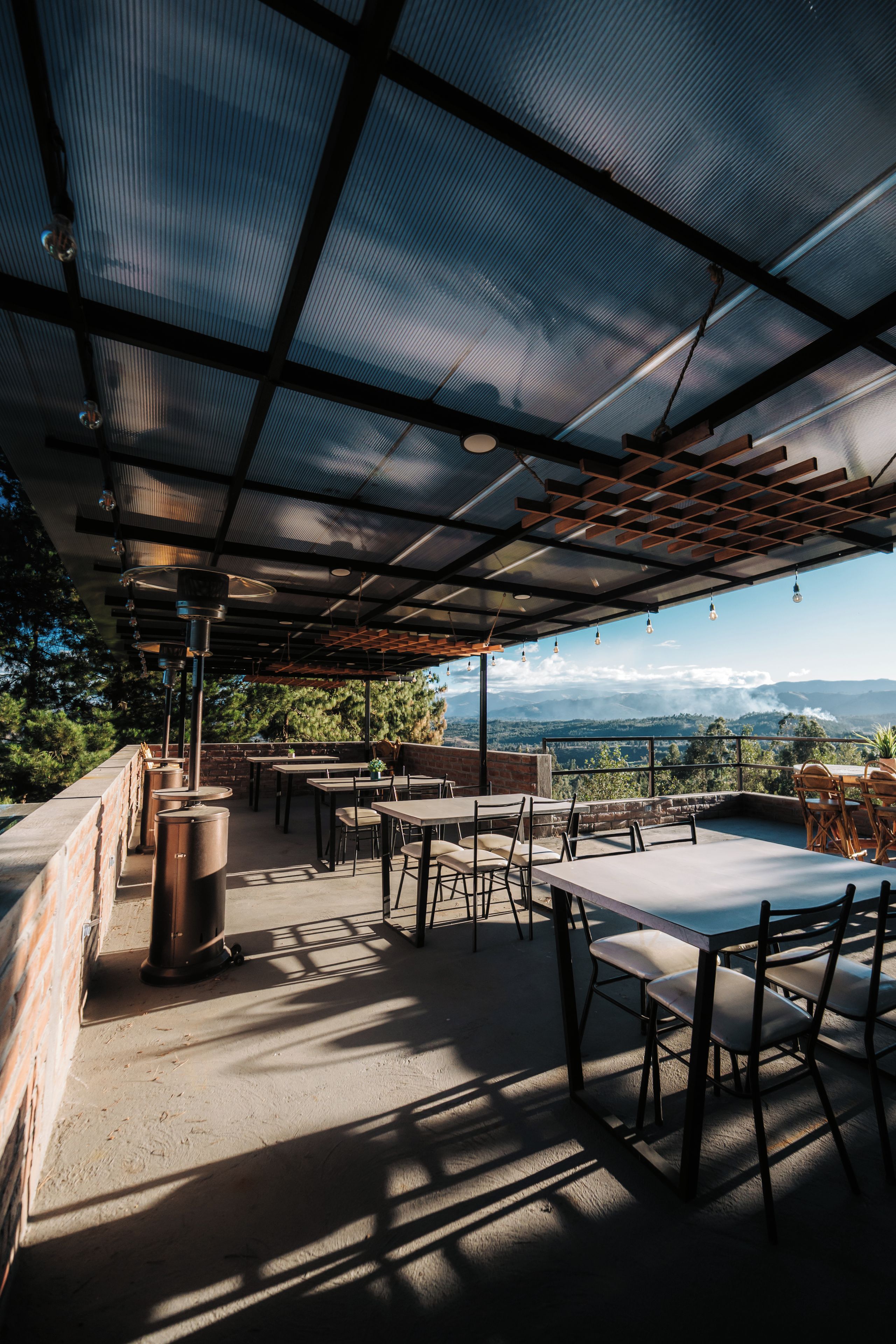 Une terrasse extérieure avec des tables et des chaises, une pergola et une vue sur le paysage.