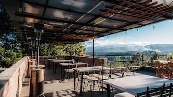 Une terrasse extérieure avec des tables et des chaises, une pergola et une vue sur le paysage.