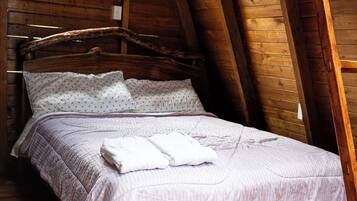 Quarto com estrutura de madeira, uma cama, uma janela e piso de madeira.