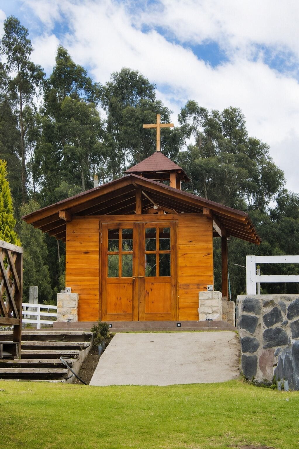 Une petite chapelle en bois, surmontée d’une croix, avec une porte d’entrée et un petit porche.