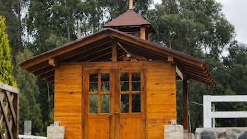 Une petite chapelle en bois, surmontée d’une croix, avec une porte d’entrée et un petit porche.