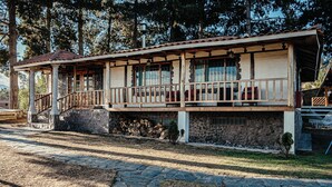 A two-story building with a stone foundation, wooden balcony railings, and a staircase leading to the upper floor.