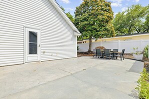 A residential backyard with a patio, a white fence, and a tree. - Newly remodeled 3BR/2BA Oceanfront Golf Cart Village Beach House (Surfside Beach)