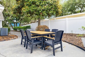 An outdoor patio with a wooden table and four chairs. - Newly remodeled 3BR/2BA Oceanfront Golf Cart Village Beach House (Surfside Beach)