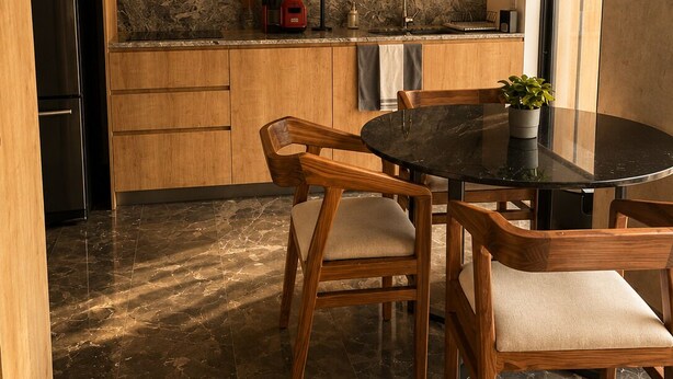A modern kitchen with wooden cabinets, a black countertop, a built-in microwave, and a dining area with a round table and wooden chairs. - New, Fully Furnished Apartment in Guadalajara-Zapopan with AC and Pool—Pet-Friendly (Guadalajara)