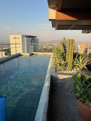 Ein Pool auf dem Dach mit Blick auf eine Stadtlandschaft und einem HSBC-Gebäude im Hintergrund.