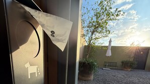 A room with a view of a courtyard, a door with a towel hanging, and a bench. - New, Fully Furnished Apartment in Guadalajara-Zapopan with AC and Pool—Pet-Friendly (Guadalajara)