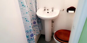 A bathroom with a white sink, a toilet, and a shower curtain. - Bloomfield Lodge Hotel (Blackpool)
