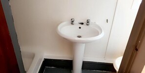 Een badkamer met een witte wastafel, toilet en deur.