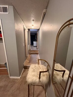 Un couloir étroit doté d’un plancher en bois, d’un tapis moelleux et d’un grand miroir.