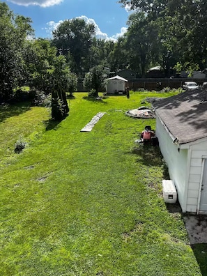 Un jardin avec une pelouse, un abri de jardin et une tondeuse à gazon.