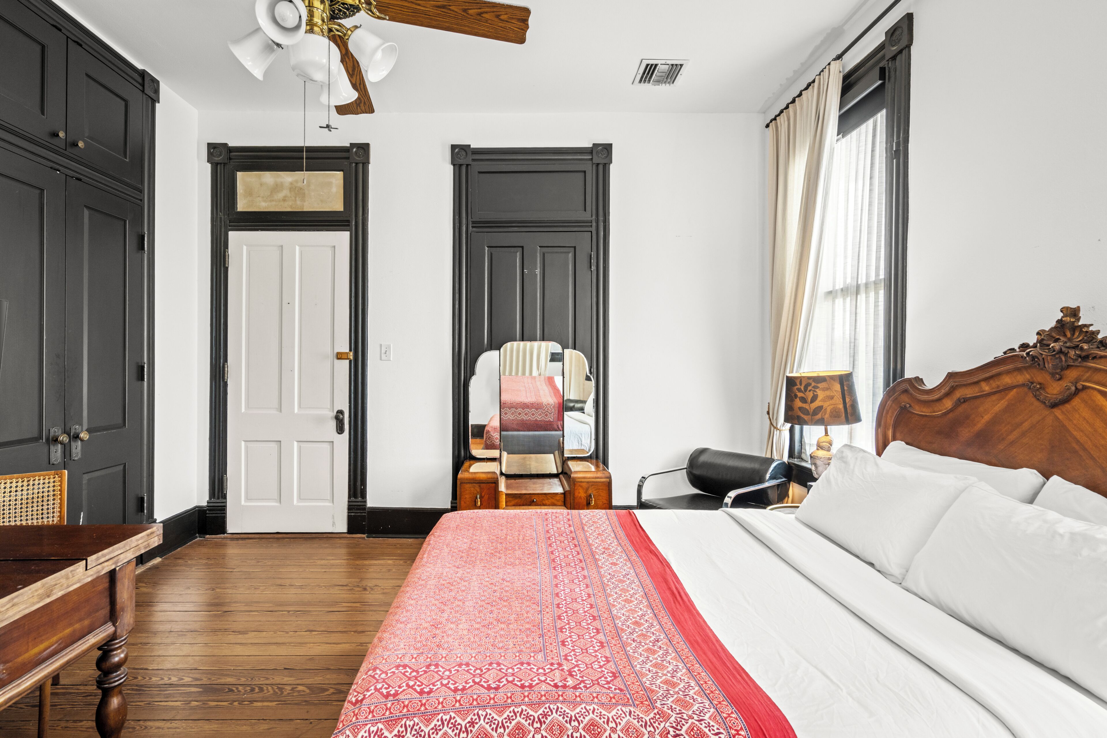 Quarto de hotel com uma cama grande, uma mesa de cabeceira de madeira, uma escrivaninha e uma cadeira.
