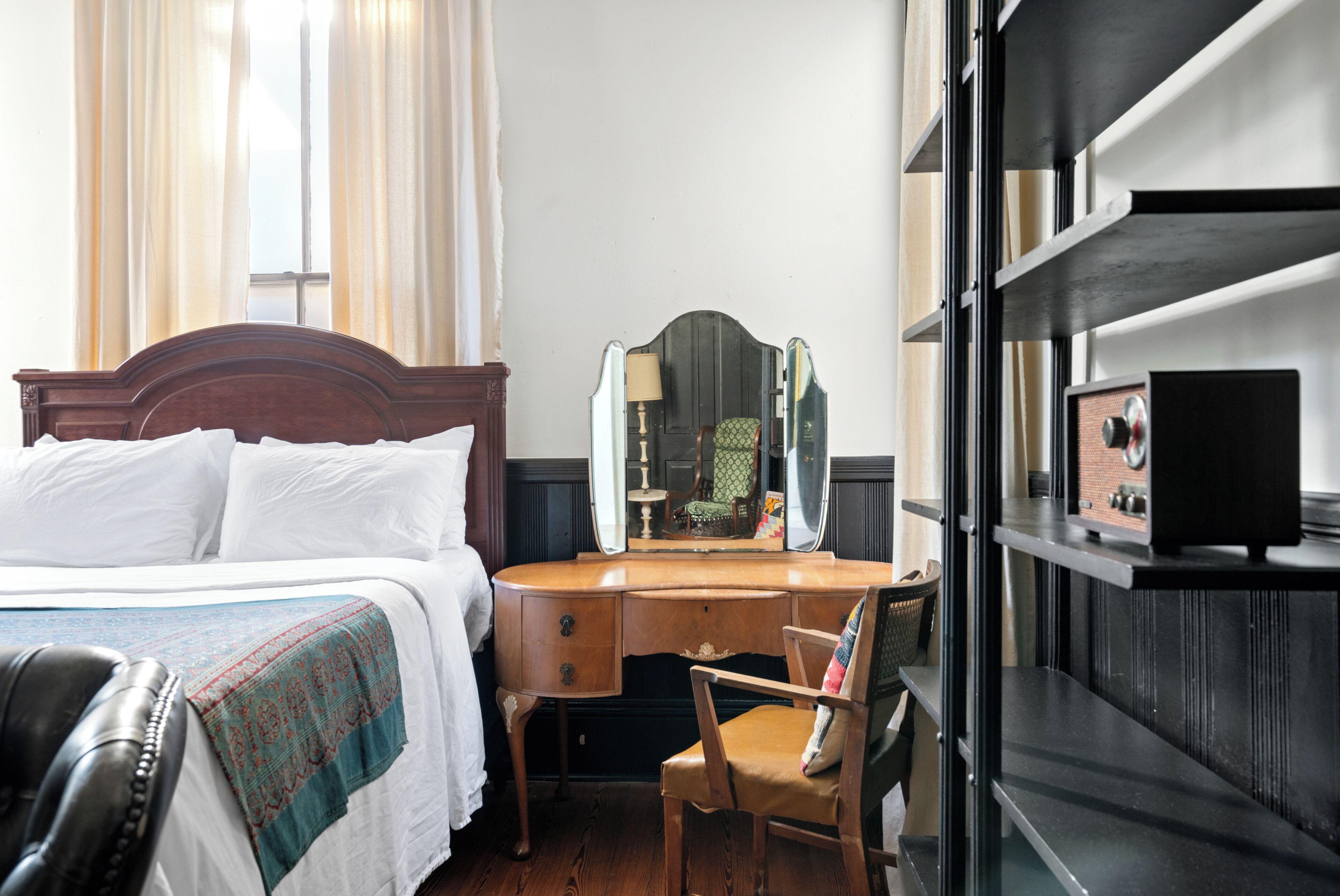 Une chambre d’hôtel avec un lit, un bureau en bois, une chaise, un miroir et un téléviseur.