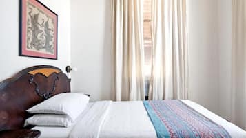Un lit avec une couverture à motifs, une tête de lit et un tableau encadré accroché au mur.