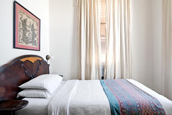 A bed with a patterned blanket, a headboard, and a framed picture on the wall.