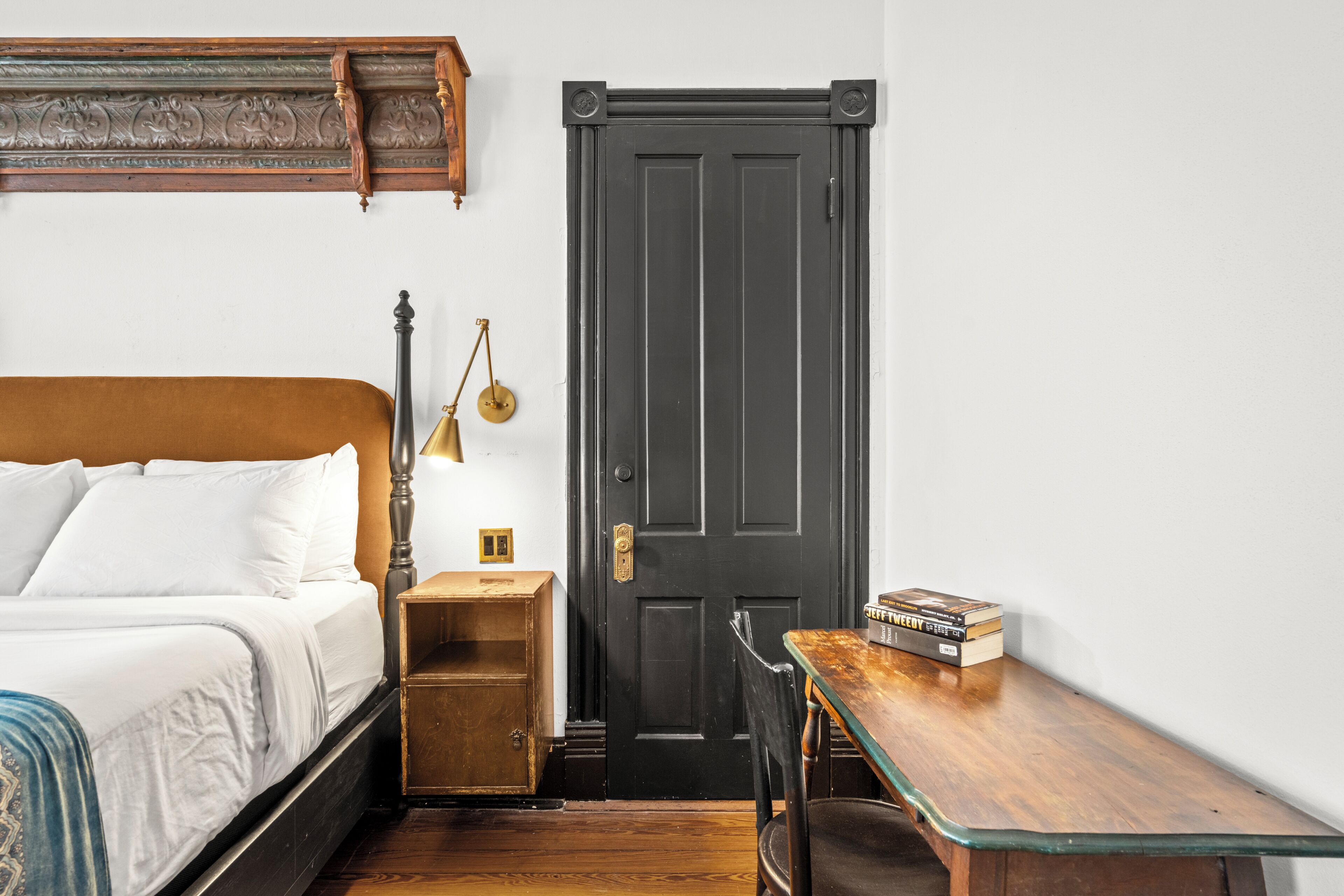 A bedroom with a bed, bedside table, lamp, and a door.