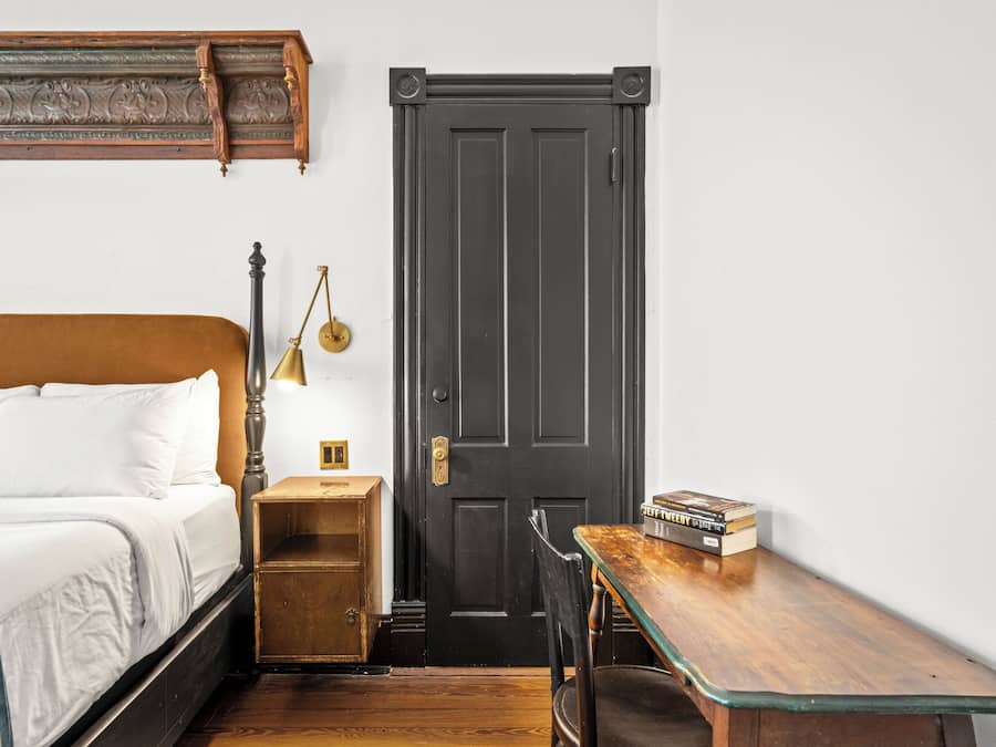 Une chambre à coucher avec un lit, une table de chevet, une lampe et une porte.