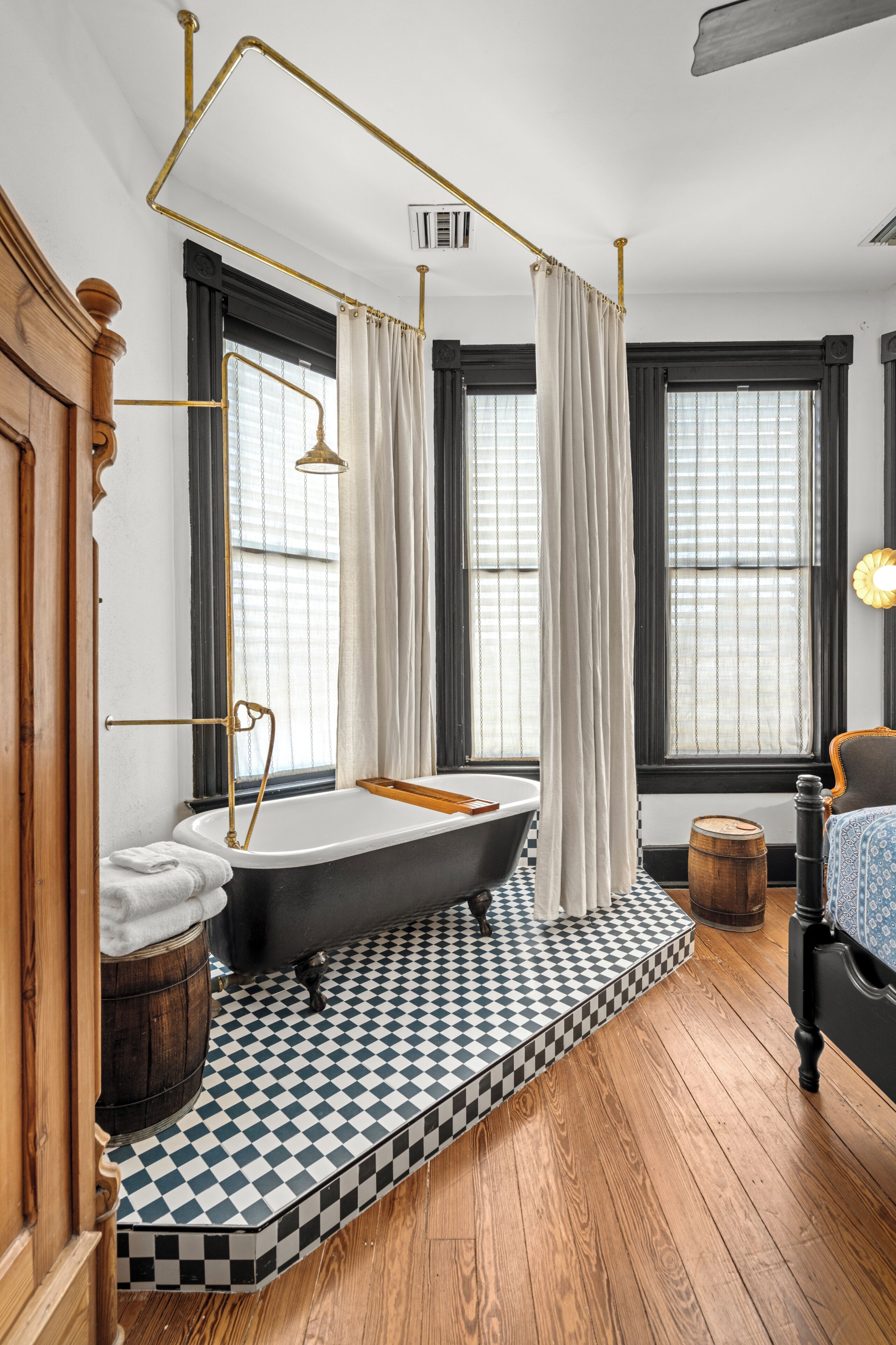 A bathroom with a freestanding bathtub, a wooden floor, and a checkered tile pattern.