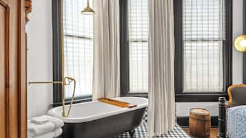 A bathroom with a freestanding bathtub, a wooden floor, and a checkered tile pattern.