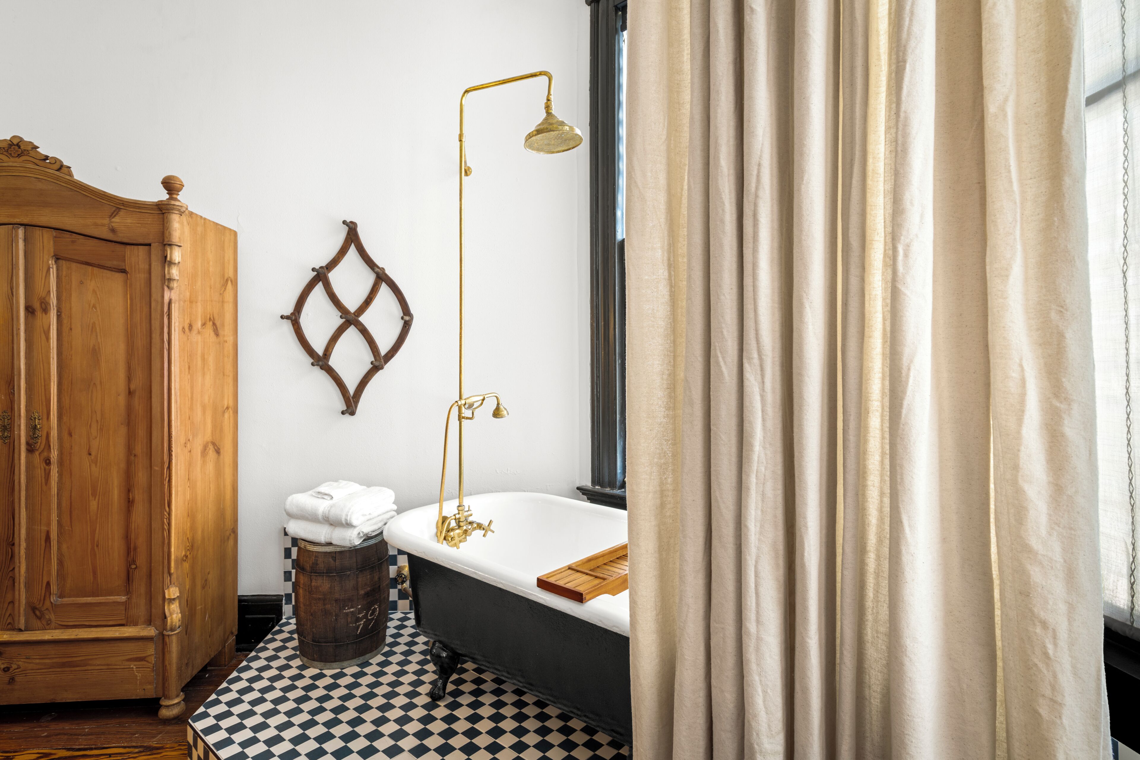 Une salle de bain avec une armoire en bois, une baignoire, un porte-serviettes mural et un carrelage à motifs carrés.