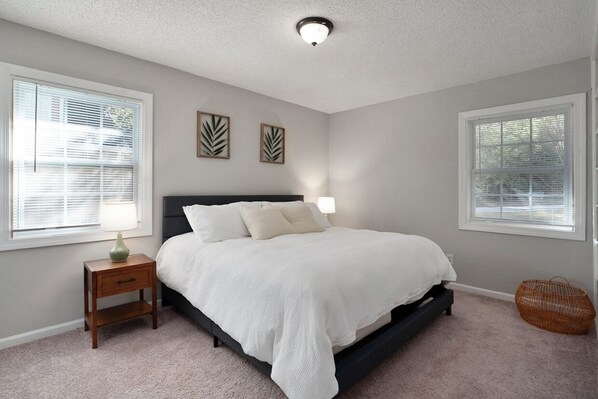 A bedroom with a bed, bedside tables, and wall art. - Modern 3 Bedroom River Retreat in Heart of Athens (Athens)