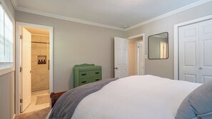 Ein Schlafzimmer mit einem Bett, einer grünen Kommode, einer Tür und einem Spiegel an der Wand.